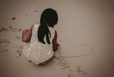 蹒跚学步的孩子在沙滩上写心